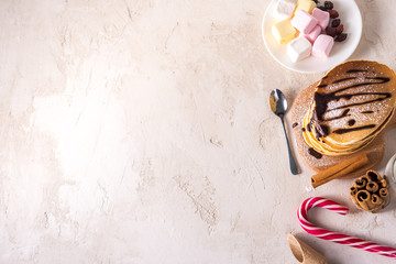  Fresh sweet pancakes with chocolate jam, cinnamon sticks and marshmallows on a gray background with place for your text.