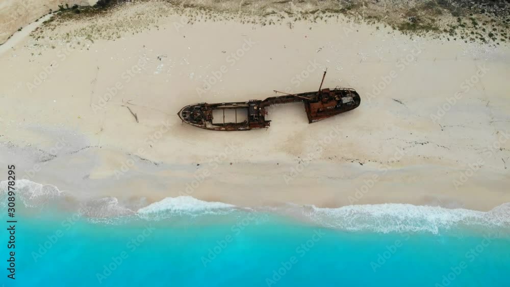 Wall mural Top down aerial view of a beautiful Navagio beach in the Ionian Sea on the shore of Zakynthos island, Greece. Drone flies back - Wall murals