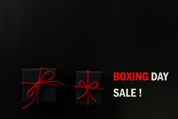 Boxing day sale online shopping.,Top view of black christmas gift boxes with red ribbon and text on black background with copy space for text.