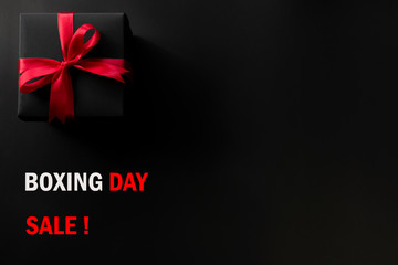 Boxing day sale online shopping.,Top view of black christmas gift boxes with red ribbon and text on black background with copy space for text.