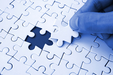 The human hand fills the last missing elements of the surface from the jigsaw puzzle. The concept of the completion of the initiated cases. phantom classic blue color tone