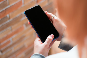 girl holding a mobile phone with a blank screen with place for text mockup
