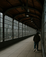 One person alone walking down long corridor at train station 
