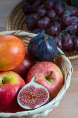 fresh fruits and red grape berries in a straw basket on a  wooden background