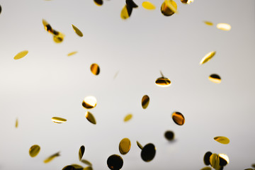 Golden falling confetti on grey background. Holiday concept.