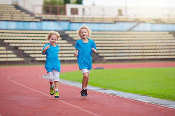 Child running in stadium. Kids run. Healthy sport.