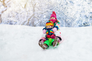 Fototapeta na wymiar Kids play in snow. Winter sled ride for children