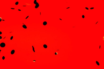 Black stylish falling confetti on red background. Holiday concept.