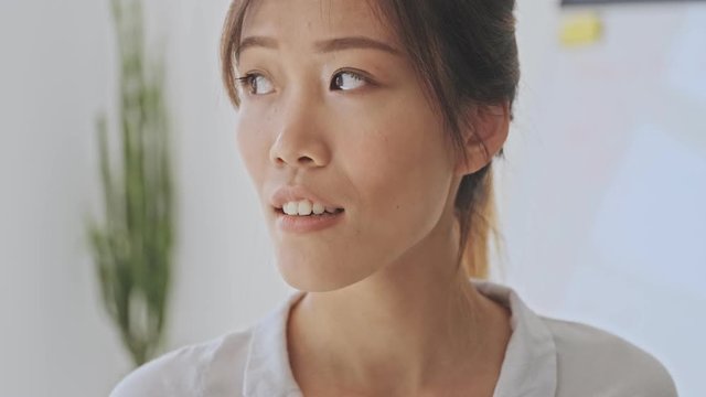 Cropped view of charming young asian business woman looking to the side and smile in the white office