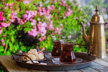 Glass Cup of turkish tea served in traditional style with summer outdore view