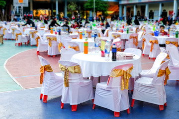 Wedding chairs in row decorated with gold color ribbon at outdoor .