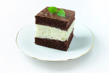 The cake with chocolate and milk filling lies on a white plate, white background.