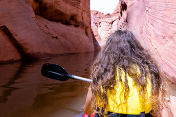 Back of young woman girl kayaking on lake powell with paddle and kayak and life vest on Antelope...