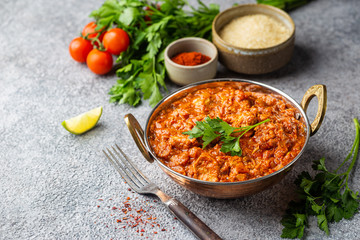 Chicken meat with tikka masala sauce, spicy curry food in iron copper pot with seasonings