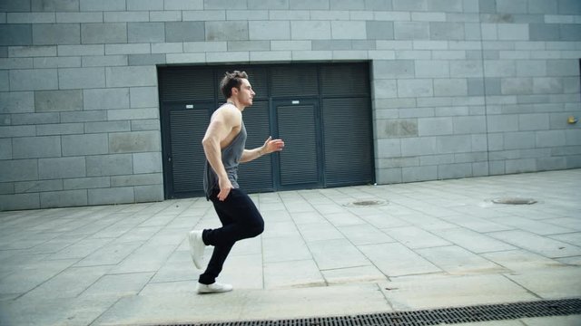 Fitness man running on urban street in slow motion. Male runner jogging outdoor.