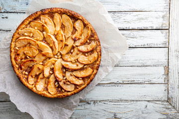 Homemade delicious fresh baked rustic apple pie on white wooden background, top view