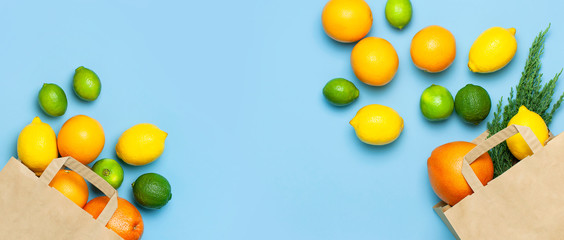 Creative background with tropical fruits. Orange, lemon, lime, grapefruit drop out of paper bag on blue background. Flat lay top view copy space. Food concept, vitamin C, disease prevention, flu