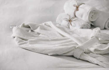 Obraz premium Clean soft bathrobe and towels on bed