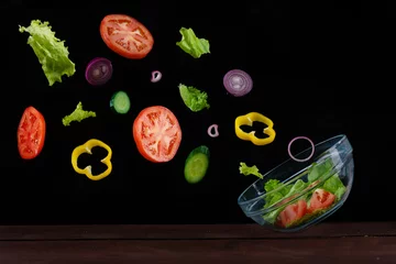 Zelfklevend Fotobehang ingredients vegetable salad flying into the bowl on a black background © Ermolaeva Olga