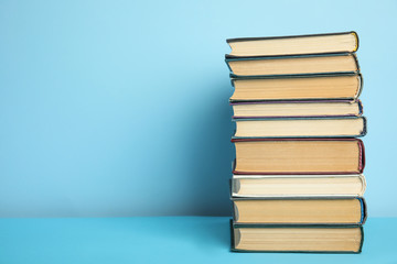 Stack of hardcover books on light blue background, space for text