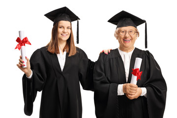 Young and senior female graduates holding diplomas