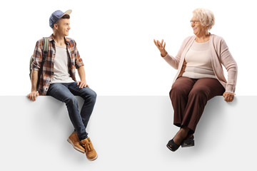 Grandmother and grandson sitting on a panel and talking - obrazy, fototapety, plakaty