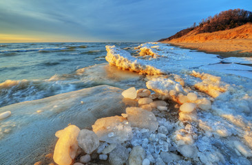 Landscape of iced winter shoreline of Lake Michigan with splashing wave, Saugatuck Dunes State...