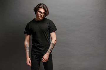 Hipster handsome male model with glasses wearing black blank t-shirt and black jeans with space for...