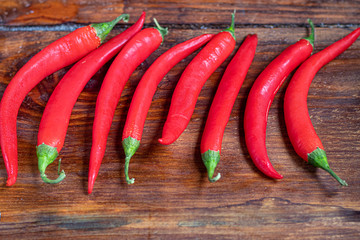 Hot red chili peppers on a wooden surface. Spicy additive in dishes.