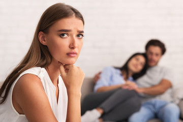 Girl Looking At Camera While Ex-Boyfriend Hugging New Girlfriend Indoor