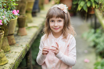 Obraz premium Little girl playing with flowers in greenhouse.