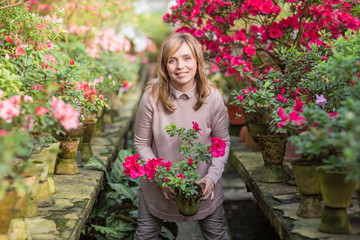 Beautiful woman watering plants and gardening in greenhouse.