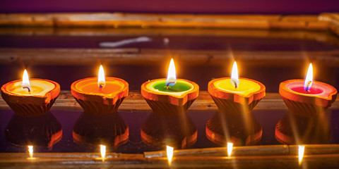 Colourful candles on the glass; flame reflecting