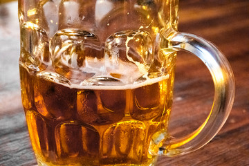 glass of beer with foam on wooden table close up