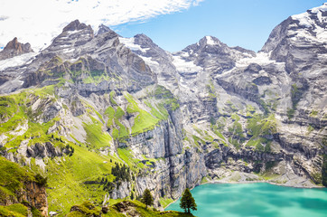 Fototapeta na wymiar Amazing top view of Oeschinensee lake by Kandersteg, Switzerland. Turquoise lake surrounded by steep mountains and rocks. Swiss Alps. Switzerland in the summer season. Tourist destinations