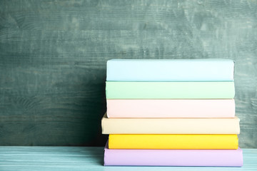 Stack of colorful books on light blue wooden table