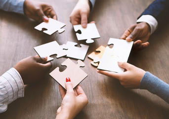 Colleagues assembling jigsaw puzzle together at office
