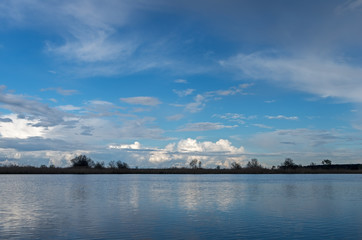 Incredibly beautiful blue sky with white cumulus clouds over water