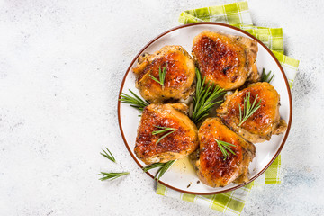 Baked chicken thighs with herbs on white plate.