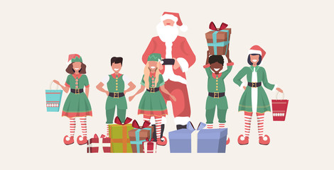 santa claus with mix race elves standing together near gift boxes merry christmas happy new year holiday presents concept horizontal full length sketch vector illustration
