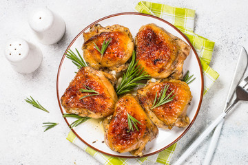 Baked chicken thighs with herbs on white plate.