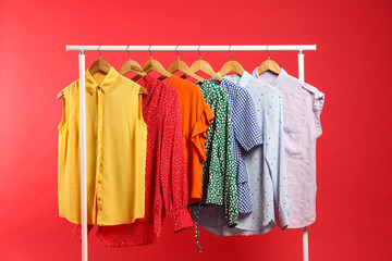 Bright clothes hanging on rack against red background. Rainbow colors