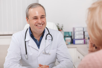 Cheerful mature male doctor talking to a patient