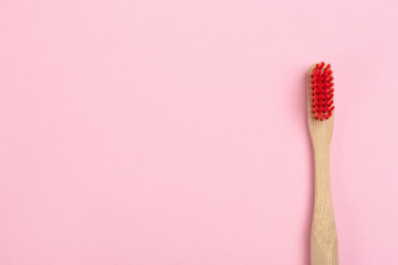 Toothbrush made of bamboo on pink background, top view. Space for text