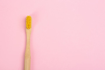Toothbrush made of bamboo on pink background, top view. Space for text