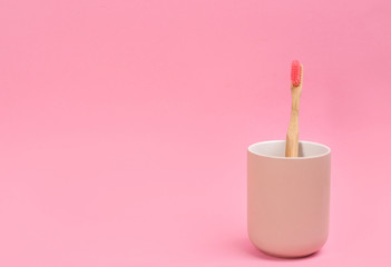 Toothbrush made of bamboo in holder on pink background. Space for text