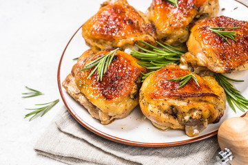 Baked chicken thighs with herbs on white plate.