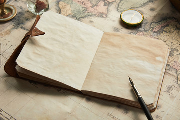 vintage blank notebook with fountain pen near compass on map background