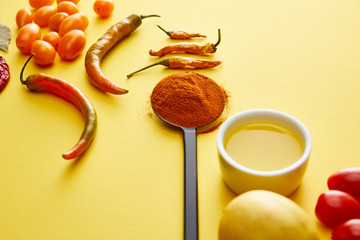 Chili peppers with spice and olive oil on yellow background