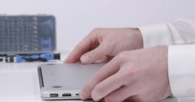 Service worker closing laptop case in white walled lab in 4k